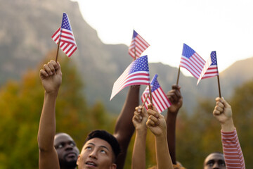 Happy diverse friends raising flags of usa in garden