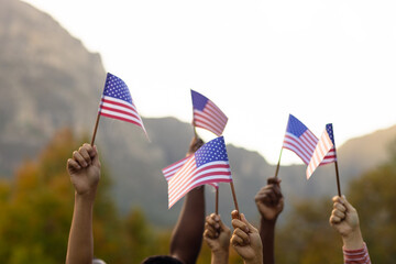Diverse friends raising hands with flags of usa in garden