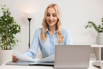 Happy secretary working with documents at table in office