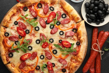 Tasty pizza and ingredients on black table, top view