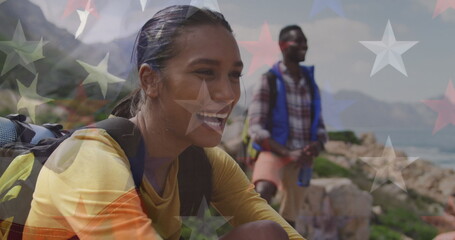 Image of american flag over smiling diverse couple sitting in mountains