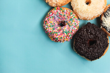 group of donuts with various flavors, on a blue background with negative space