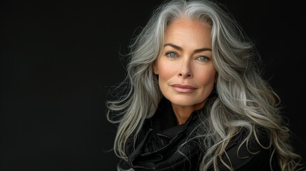 Fototapeta premium A Striking Portrait of a Mature Woman with Long Grey Hair and Expressive Eyes, Posing Confidently against a Black Background