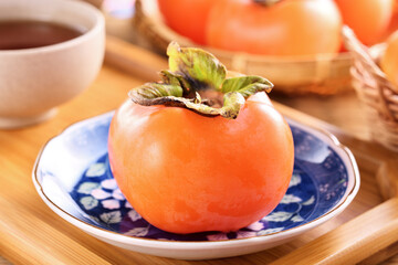 Delicious ripe persimmon fruit on wooden table.  