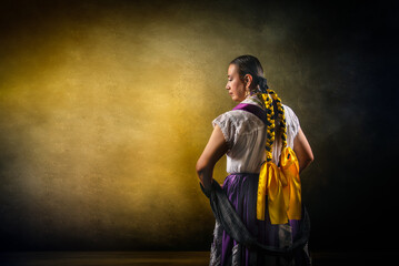 A woman wearing a yellow and purple dress with a yellow ribbon