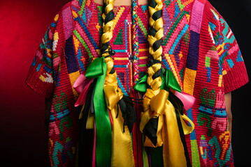 A woman wearing a colorful outfit with a long yellow and green ribbon