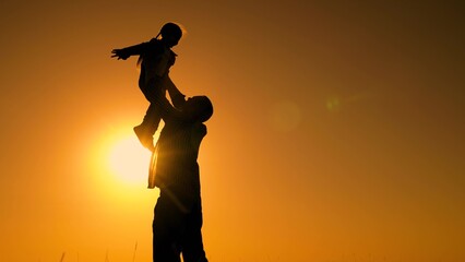 Father throws happy baby daughter into sky. Family game with child in outdoor. Dad is playing with...