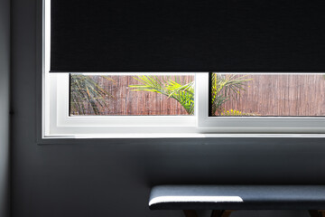 window with blockout blind halfway down revealing tropical backyard and minimalist interior, focus...