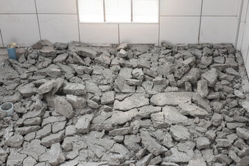 Scrap concrete in toilet room, construction site. Demolished work of tile and concrete floor. To...