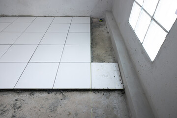 Tile floor under construction in perspective view by white square ceramic tile. Finishing material for interior, decoration, installation on concrete surface floor in bathroom, kitchen and shower room