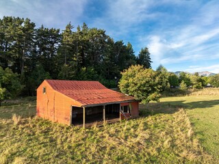 Obraz premium Red barn on farmland at sunset in Hanmer Springs, Canterbury, New Zealand.