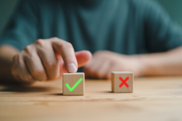 Businessman's hand chooses the one wooden cube block with the green right for approve and reject...