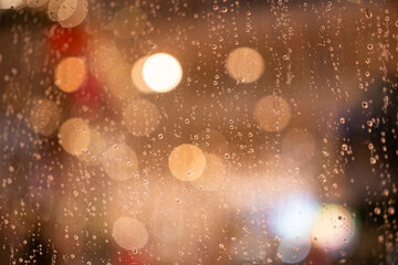 Raindrops water droplets trickling down on wet clear window glass during heavy rain against blurred...
