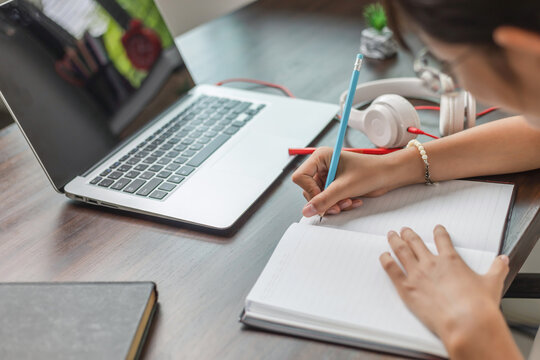 girl using pencil write notes online learn on laptop at home.