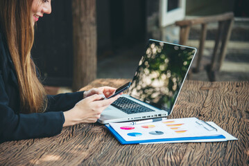 Asian Female freelance using laptop at home office desk. Woman reading financial graph chart...