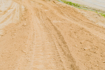 Backhoe tracks in loose dirt at rural construction site.