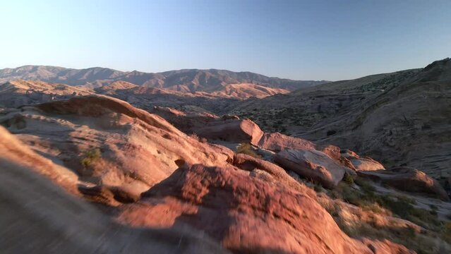 Drone flying through a gap in rocks of the Vasquez natural park, sunset in USA