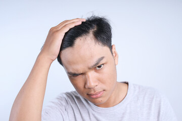 Young Asian Man With Dark Hair Touches His Hair With Right Hand, Corrects His hair Isolated On White Background