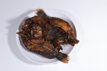 Dried salted fish is served on a plain white plate and base