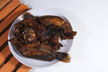 Dried salted fish is served on a plate and wooden coaster