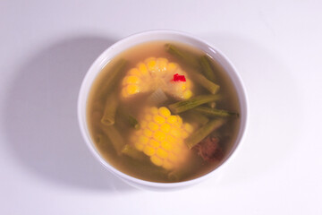 sweet and sour corn vegetable soup with a porcelain bowl and plain white base