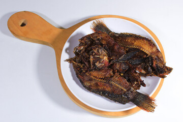 Dried salted fish is served on a plate and wooden coaster