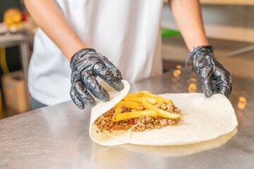 Assembling a fajita with meat and fries