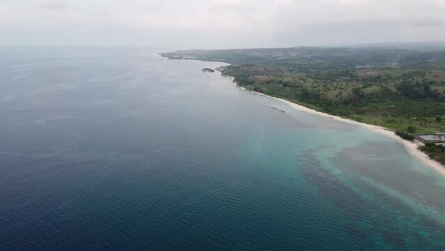 Aerial view of tropical beach and sea water with small waves close to mountains. Travel tropical concept.
