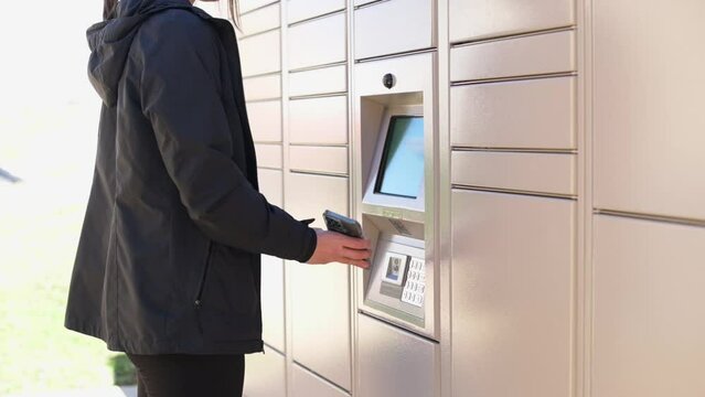 A woman accessing an outdoor self-service post locker, highlighting the convenience of modern package retrieval.