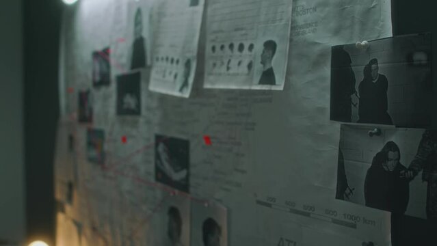 Close-up pan no people shot of criminal profiles, APB on suspects, murder photos, pinned to forensic crime map on wall in federal bureau or law enforcement agency