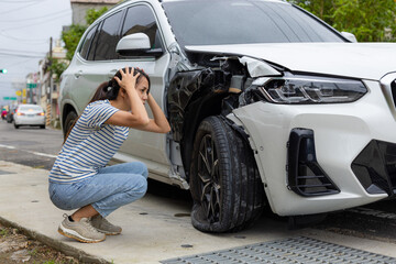Frightened woman sits in front of crashed car