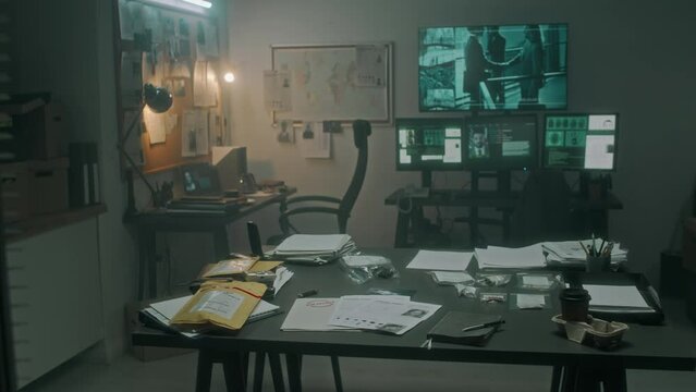 Full pan no people shot of screen with satellite surveillance, computer screens with suspect profile, fingerprints, crime maps, table with forensic evidence, at detectives office at police department