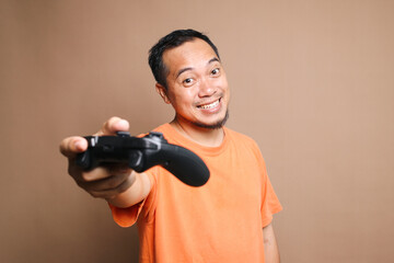 Asian man showing joystick for playing video games isolated on beige background