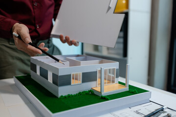 an architect is working on blueprint to finish in on time, architect is designing model house in...