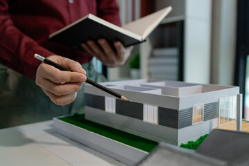 an architect is working on blueprint to finish in on time, architect is designing model house in...