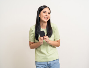 Pretty young asian woman using cellphone standing on isolated white background. Happy Excited...