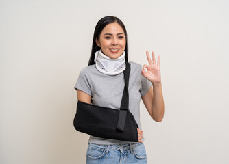 Happy young asian woman broken arm on isolated background. Asian female put on plaster bandage cast...