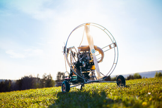 Paragliding machine for paragliding flights on green grass against the bright sun. Preparing paralet with a gasoline engine for flights. Extreme sports