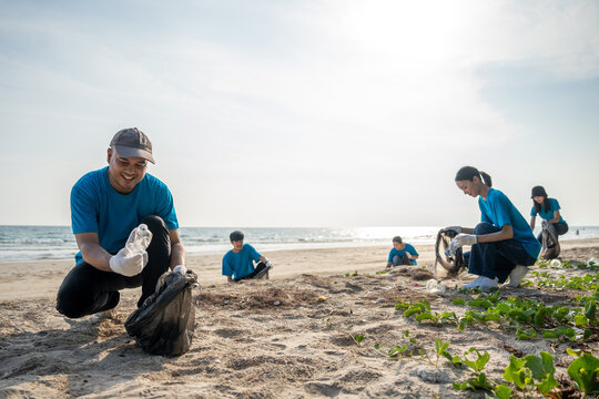 Group teamwork volunteer pick up the plastic bottle on the beach. People male and female Volunteer with garbage bags clean the trash on the beach make the sea beautiful. World environment day CSR.