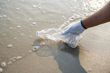 Close up hand pick up the plastic bottle on the beach. People male and female Volunteer with...