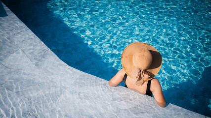 Young Asian woman with hat relaxing beside the pool at luxury hotel. travel and summer concept background.,cover banner concept vocation summer