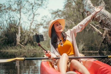 Holiday travel activities. Happy asian woman rowing a canoe or kayak in mangrove forests. Young...