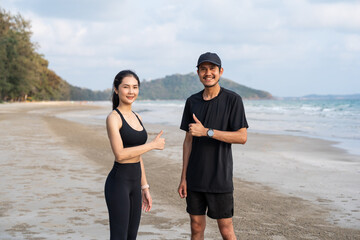 Asian Couple stretching arms and legs before running outdoors sea sand beach. Sporty people warm up...