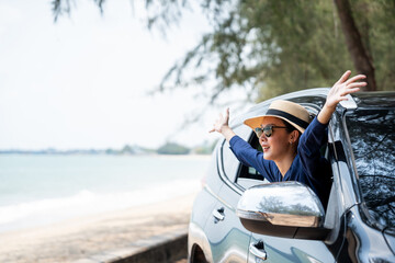 A young beautiful asian woman travel to the sea by car on a bright day. With beautiful blue sky....