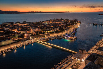 Zadar, Croatia - Aerial view of the illuminated City Bridge (Gradski most) with the old town of Zadar, Cathedral of St. Anastasia tower, yacht marina and golden sunset sky