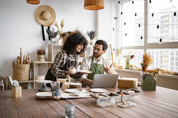 Portrait of mature man and young curly woman creating online catalogue of available goods at decor...