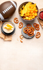 Snacks for watching an American football game. Beer, chips, pretzels, sauce on wooden background