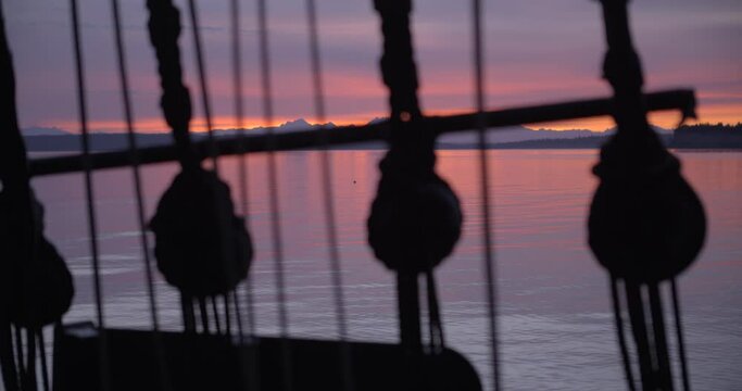 1700s sailing ship underway at sunrise. Rack focus between the water and ratlines.