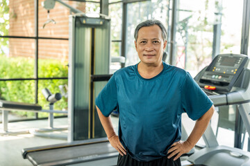 Senior asian man wearing sportswear warming up in fitness gym before exercise. Mature man stretching arm before running. Training athlete work out