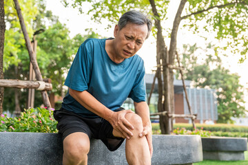 Mature man tired and leg pain during jogging at nature park. Runner has sore knees because he has...